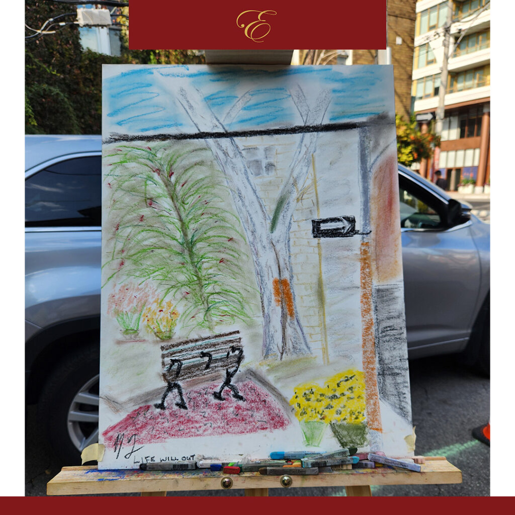 The image depicts a pastel artwork set up on an easel along a city street. The drawing portrays a serene, outdoor space, possibly a small urban park or garden. At the center of the scene is a simple wooden bench, resting on a reddish path. The bench is unoccupied, yet its placement evokes a sense of quiet invitation, as though it’s waiting for someone to sit and enjoy the surroundings. Beneath the bench, the words **“LIFE WILL OUT”** are written in soft, hand-drawn lettering, suggesting themes of resilience and the persistence of life. In the background, vibrant greenery thrives. A tall tree with bare branches stands beside a stone wall, while lush ferns and potted flowers add touches of life and color to the scene. Yellow blooms in a pot brighten the lower corner of the image, contrasting against the muted tones of the street beyond. A car parked in the background reminds viewers that this is an urban setting, yet nature seems to be flourishing regardless.